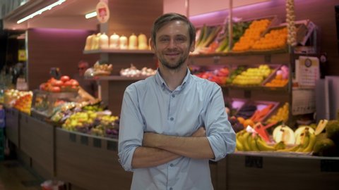 Portrait of man a grocery store clerk or owner in front of a vegetable counter
