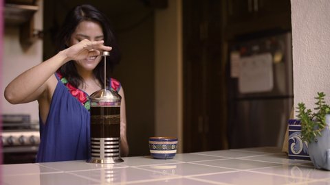 A woman makes coffee in the kitchen of her Spanish style home in Mexico with natural light.   库存视频