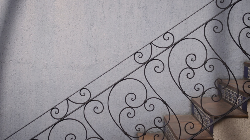 A woman in Mexico carries fresh coffee upstairs in a Spanish style building while wearing a traditional blue dress.