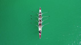 Aerial drone top down view loop video of sport canoe operated by team of young women in emerald clear sea