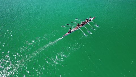 Aerial drone top down view video of sport canoe operated by team of young women in emerald clear sea