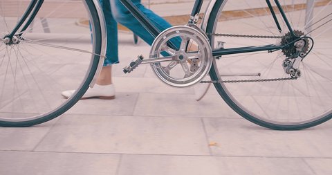 Slow motion 4K. Businesswoman person in white go with her retro bicycle near modern buildings in city. Park area in downtown.
 Vídeo Stock