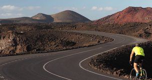 Man cyclist biking on road bike cycling in amazing nature landscape. Professional cyclist athlete cycling riding bicycle training in Lanzarote, Canary Islands, Spain, Europe.