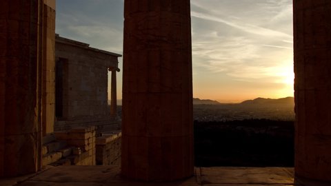 Time lapse of the sun appearing behind an ancient column in the Propylaea of the Acropolis and the city of Athens, Greece in the background