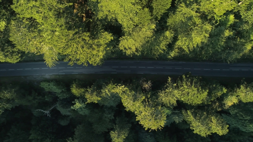 Aerial of a mountain road with a car coming in from left to right at sunset