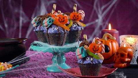 Happy Halloween candyland drip cake style cupcakes with lollipops and candy in party table setting.