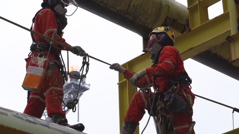 KELANTAN, MALAYSIA - SEPTEMBER 25th, 2019 : A group of industrial abseiler complete with Personal Protective Equipment (PPE) working at height nearby oil and gas pipeline for painting activities.