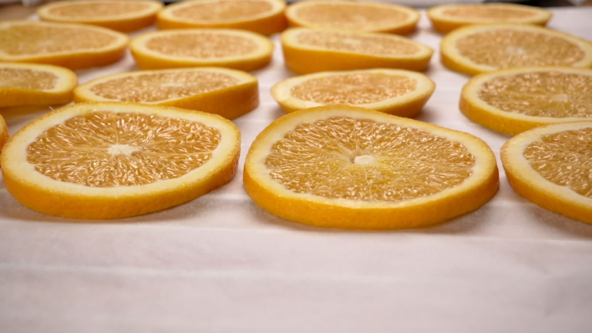 Hand lay orange slices on baking paper. Close up. 