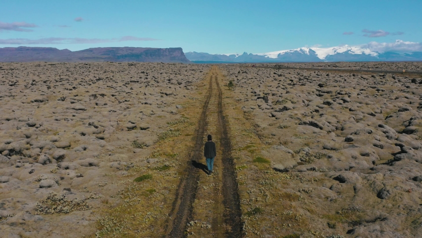 Aerial view of a woman walking next to green Lava fields moss-covered hills. Southern Iceland.