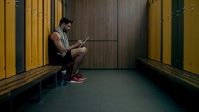 handsome sportsman using digital tablet in locker room