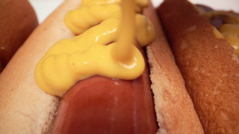 Extreme macro of beef hot dogs with mustard being squeezed on it. 