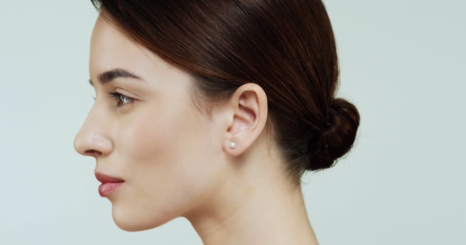 Adverisement of the beauty skin product - young pretty Caucasian woman with nice skin face turning her head to the camera and smiling to the camera on the wall background. Close up. Portrait.