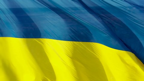 4k Ukrainian yellow blue flag, blue sky background, closeup,