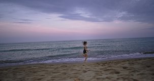 Large video of a beautiful young lady running professional on a beach side in the morning wearing a sportswear. slow