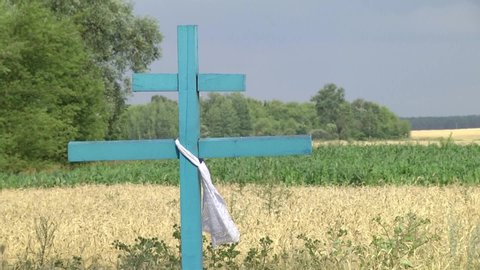 Christian orthodox cross next to a field of wheat. Soft focus. Scenic view of old wooden orthodox cross.
