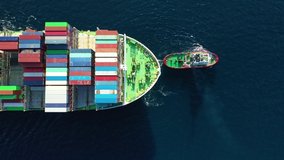 Aerial top down tracking video of Container cargo Ship carrying load in truck-size colourful containers in deep blue open ocean sea 