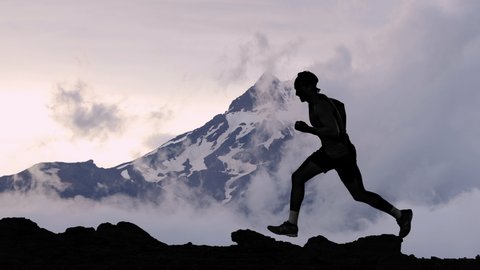 CINEMAGRAPH - seamless loop video. Running man athlete silhouette trail running in mountain summit background clouds. Man on run training outdoors active fit lifestyle. Looping Motion photo image. 库存视频
