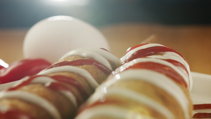 Close-up on ready-made corn dog pouring mustard. Slow motion video