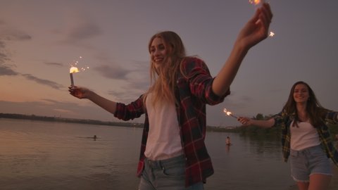 Beautiful women in summer with sparklers dancing in slow motion on the beach at night. స్టాక్ వీడియో