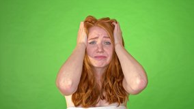 Desperate ginger woman with her hands in her hair. Studio clip