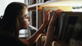 Girl in eyewear searching for the book and looks at the light beam through the shelves. - Powered by Shutterstock - Get 15% off with code: PIKWIZARD15