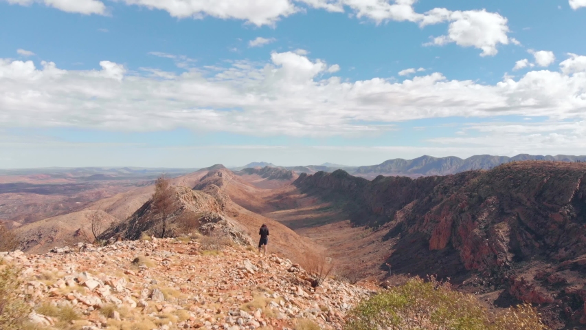 Aerial drone shot along West MacDonnell Ranges, blue sky and white cloud