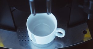 Coffee machine pouring black coffee into white cup. Coffee maker at work. Red camera.