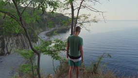 A young man from behind goes to the cliff and looks at the bottom. - Powered by Shutterstock - Get 15% off with code: PIKWIZARD15