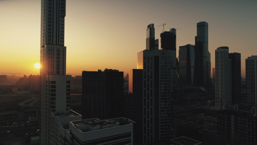 Russia sunrise orange sky. Helicopter best romantic cityscape Moscow city  sun horizon from a great height. Modern complex business steel glass skyscrapers silhouettes view against the sun.  Royalty-Free Stock Footage #1038768926