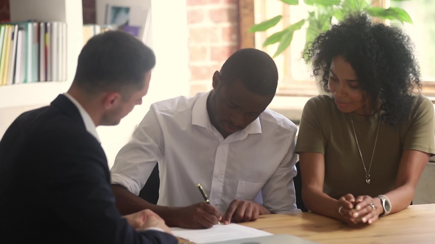 Real estate agent businessman and black couple make deal family listens realtor telling offering new property parties signing lease contract feel happy handshaking, getting keys, loan mortgage concept | Shutterstock HD Video #1038796160