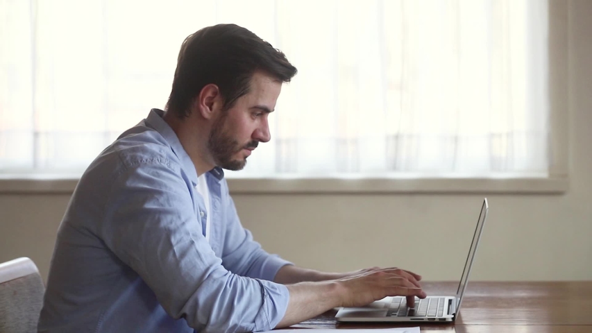 Self-employed young man sitting at desk side view, thinking typing e-mail solve business issues distantly doing remote job away from the office having busy fruitful workday at home freelancing concept | Shutterstock HD Video #1038796307