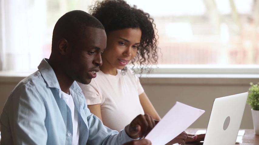 African family sit at desk husband holds paper dictates info wife typing on pc, filling internet application form on website make credit request or calculating incomes expenses feels satisfied concept Royalty-Free Stock Footage #1038796319