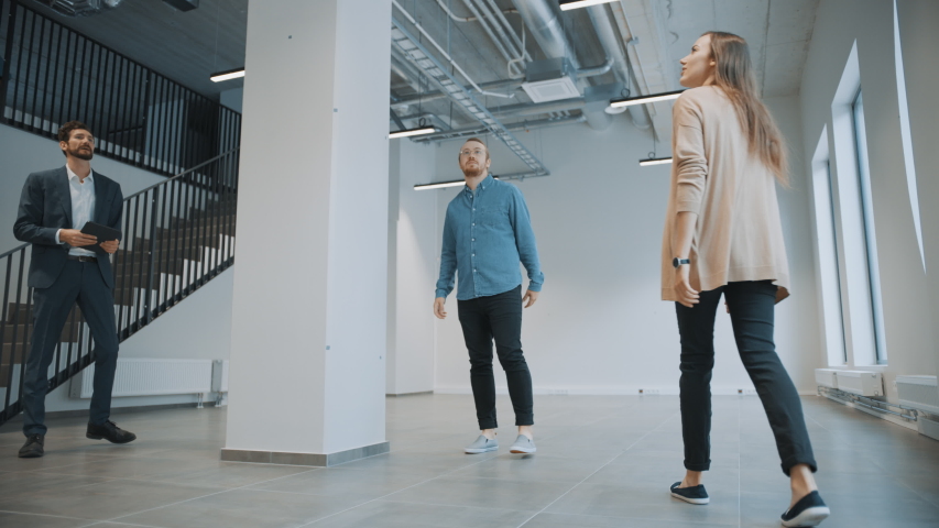 Real Estate Agent Showing a New Empty Office Space to Young Male and Female Hipsters. Entrepreneurs Meet the Broker with a Tablet and Discuss the Facility They Wish to Purchase or Rent. | Shutterstock HD Video #1038801293