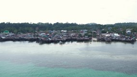 Aerial Drone Video flying above Fishing Village of Tanjung Binga in Belitung Island Indonesia. Fishing Boat on Clear water, village houses