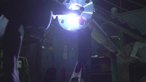 Close up shot of a Malay welder tig welding a flange and pipe with wearing a safety industrial mask (Kilang di Malaysia)