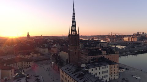Stockholm downtown city skyline at sunrise aerial view. Drone shot orbiting around church tower building on Riddarholmen island in central Stockholm. Old Town, Gamla stan landmark, Capital of Sweden