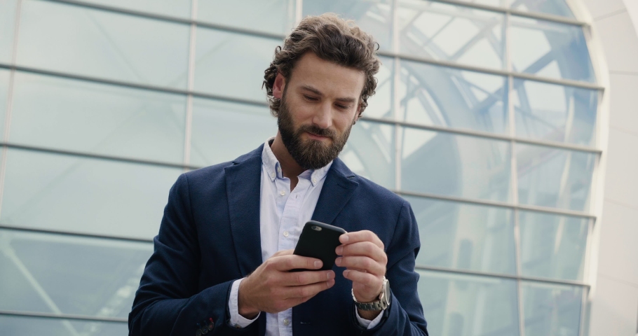 Businessman browsing his Smartphone near modern Office Building. Attractive Man in formal wear using Mobile Phone. Apps Royalty-Free Stock Footage #1038809864