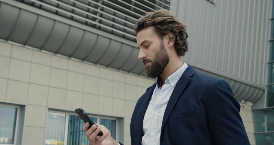 Successful Startupper talking Business-call near modern Business center. Handsome stylish man using his Phone for Business Conversation. Bearded Man walking. Business Lifestyle. People. Man. Apps. Royalty-Free Stock Footage #1038809936