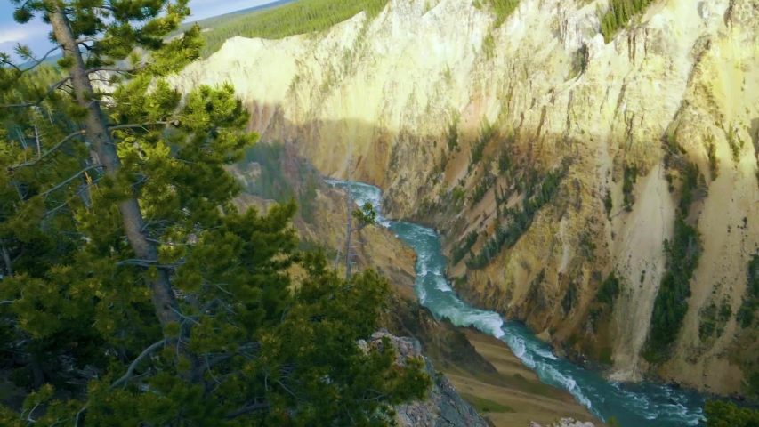 Looking down into Yellowstone Canyon, a valley with a mountain river fed by a waterfall.