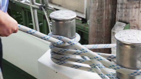 A sailor untying a rope on a boat to start sailing. Medium close up shot from the side.