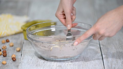 Woman confectioner makes chocolate shortcrust pastry dough in the kitchen. Adds chilled butter to the flour.