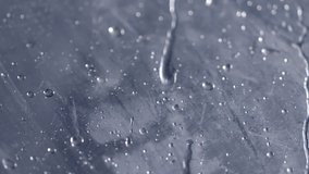 Macro view of surface of clear plastic umbrella with slow motion rain splashing and rolling down. Looping clip with transition through focus change. Recorded at 120fps.