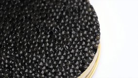 Black Caviar rotated background. High quality real natural sturgeon black caviar close-up, rotation. Delicatessen. Texture of expensive luxury caviar in tin can on white. Seafood. 4K UHD video Slowmo