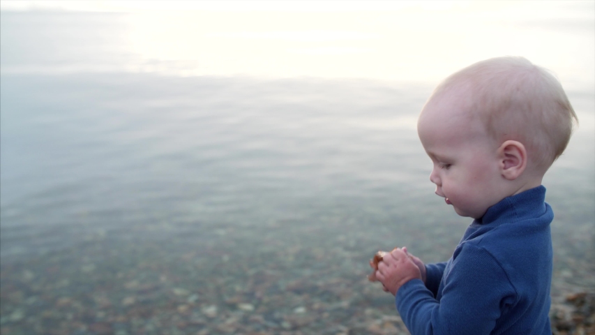 Portrait of small cute boy with sea weed in hands. Transparent water is on the background. Morning. Vladivostok, Russia