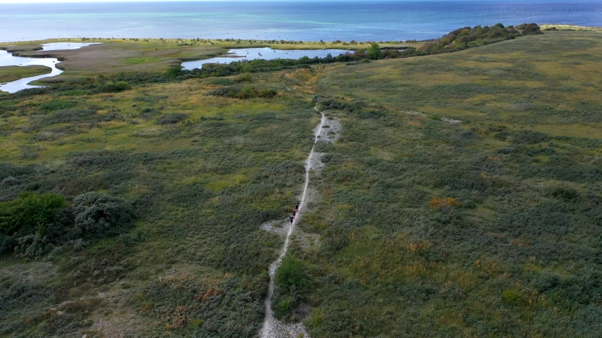 People running trail race along coastal hiking route, aerial view pan
