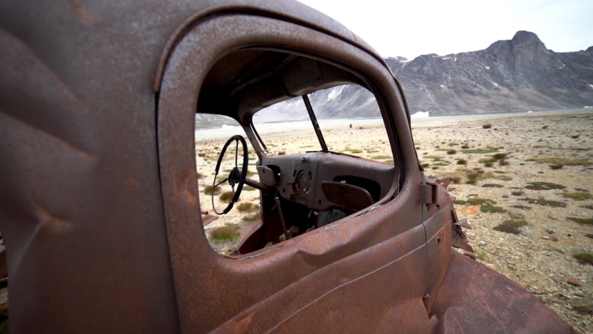 View of the Snow Covered Mountains through an Abandoned Military Vehicle. Greenland.