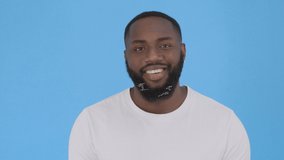 Close up portrait of hard laughing young man. Isolated on blue background 4K