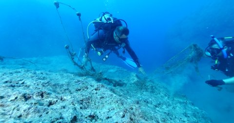 scuba divers picking old nets and fishing cages underwater ghost hunting dangerous ocean scenery driftnets