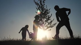 happy family of farmers a silhouette concept slow motion video. dad son and daughter children plant and water the tree outdoors lifestyle in the park. happy family little girl and boy works in the