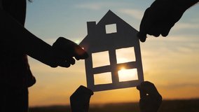 happy family construction house teamwork concept. Mom daddy and son holding home a paper house in his hands at sunset silhouette sunlight. life symbol ecology video. boy and girl,lifestyle man hold